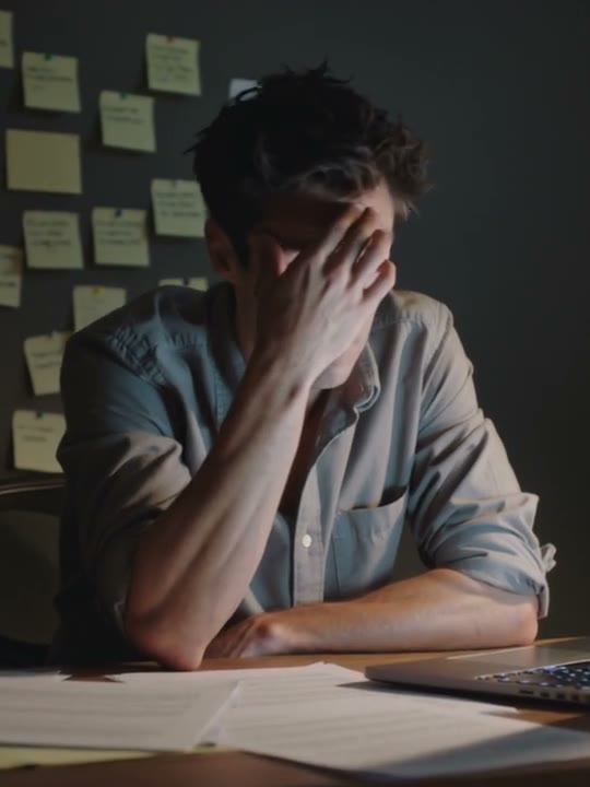 A founder working late at a desk, the wall behind covered in sticky notes